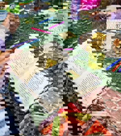 Foto af grøn dug med en bog og en tallerken med gifler og kiks. Eleverne spiser mens de læser.